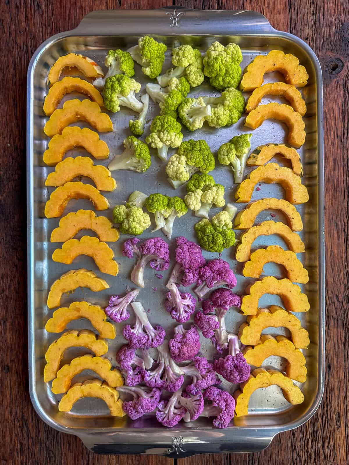 Delicata squash slices and cauliflower florets on the prepared baking sheet.