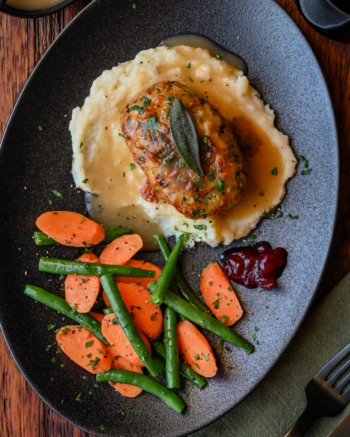 An individual turkey meatloaf served with mashed potatoes, gravy and vegetables.