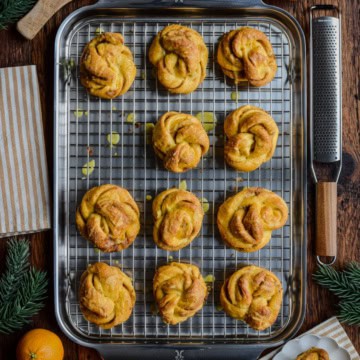 A sheet pan with Orange Cardamom Buns surrounded in a festive setting.