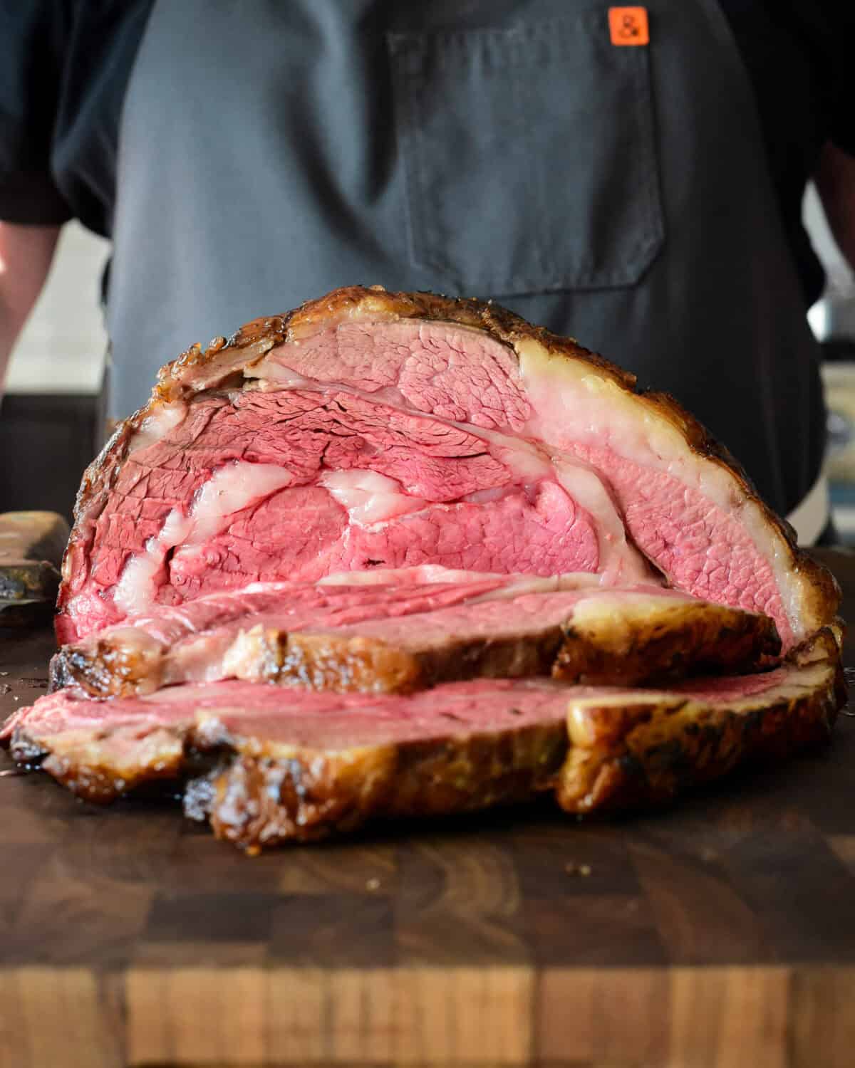 A slow roasted bone in prime rib roast slice open to reveal a perfect medium rare interior.