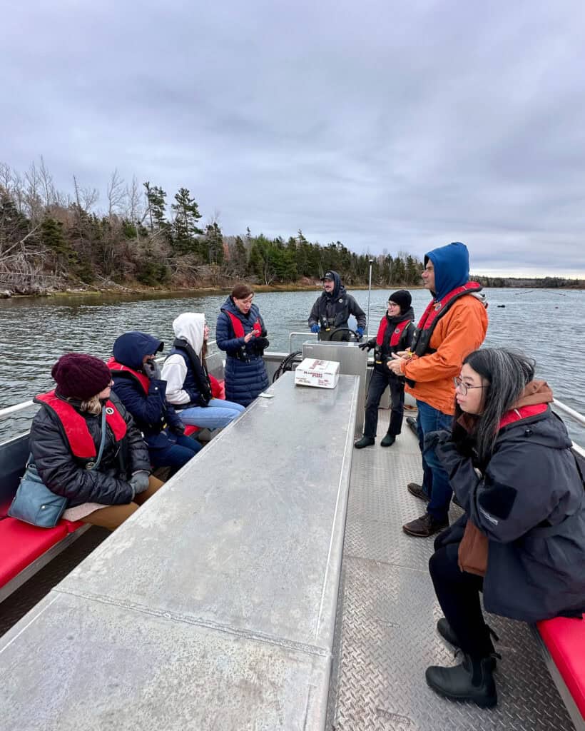 A group having a tour of oyster fishing on a boat.
