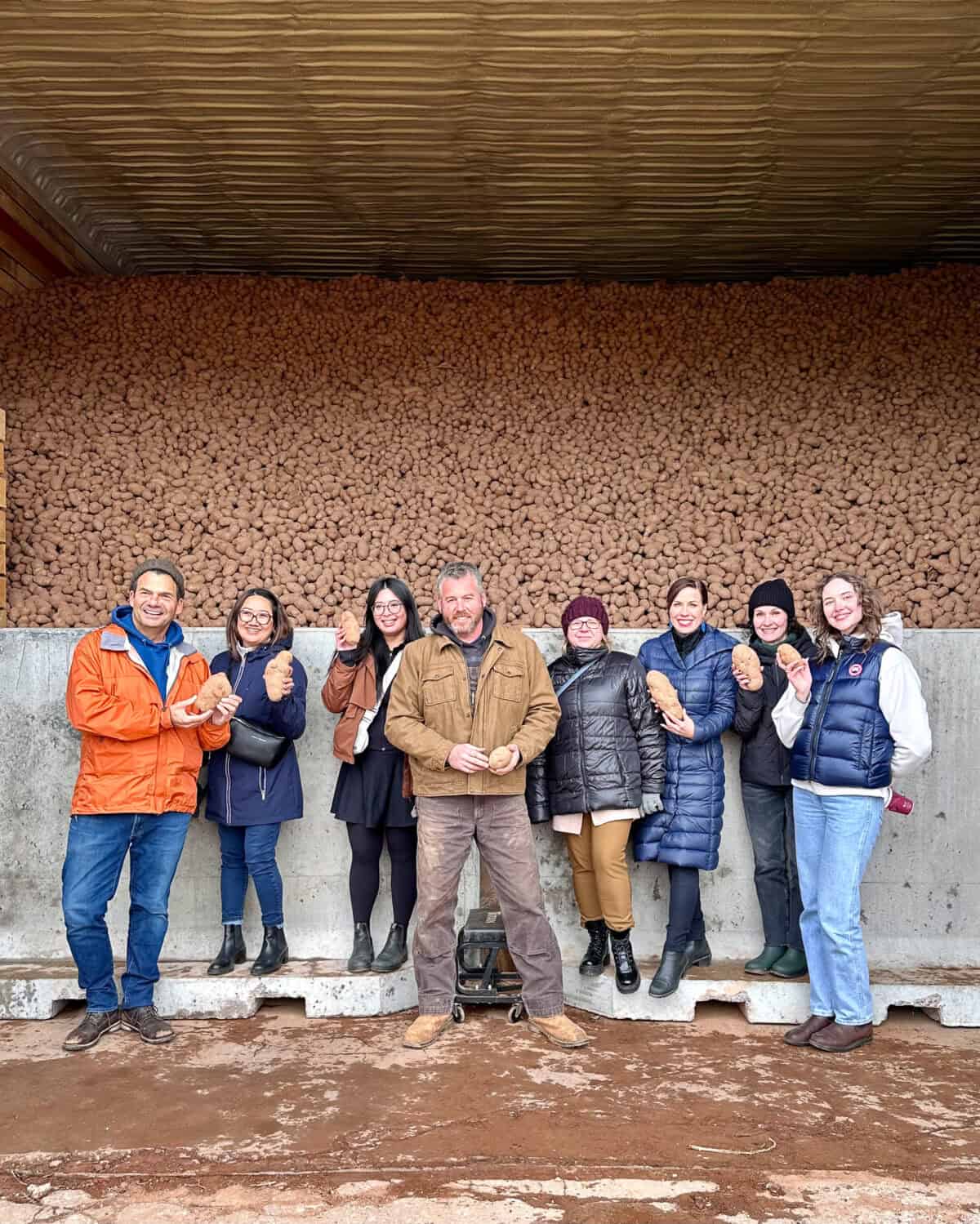 Our tour group at a potato farm in PEI standing infront of a bin that is carring 3 million pounds of potatoes.