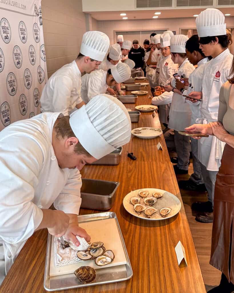 A row of junior chefs shucking oysters for a competition.