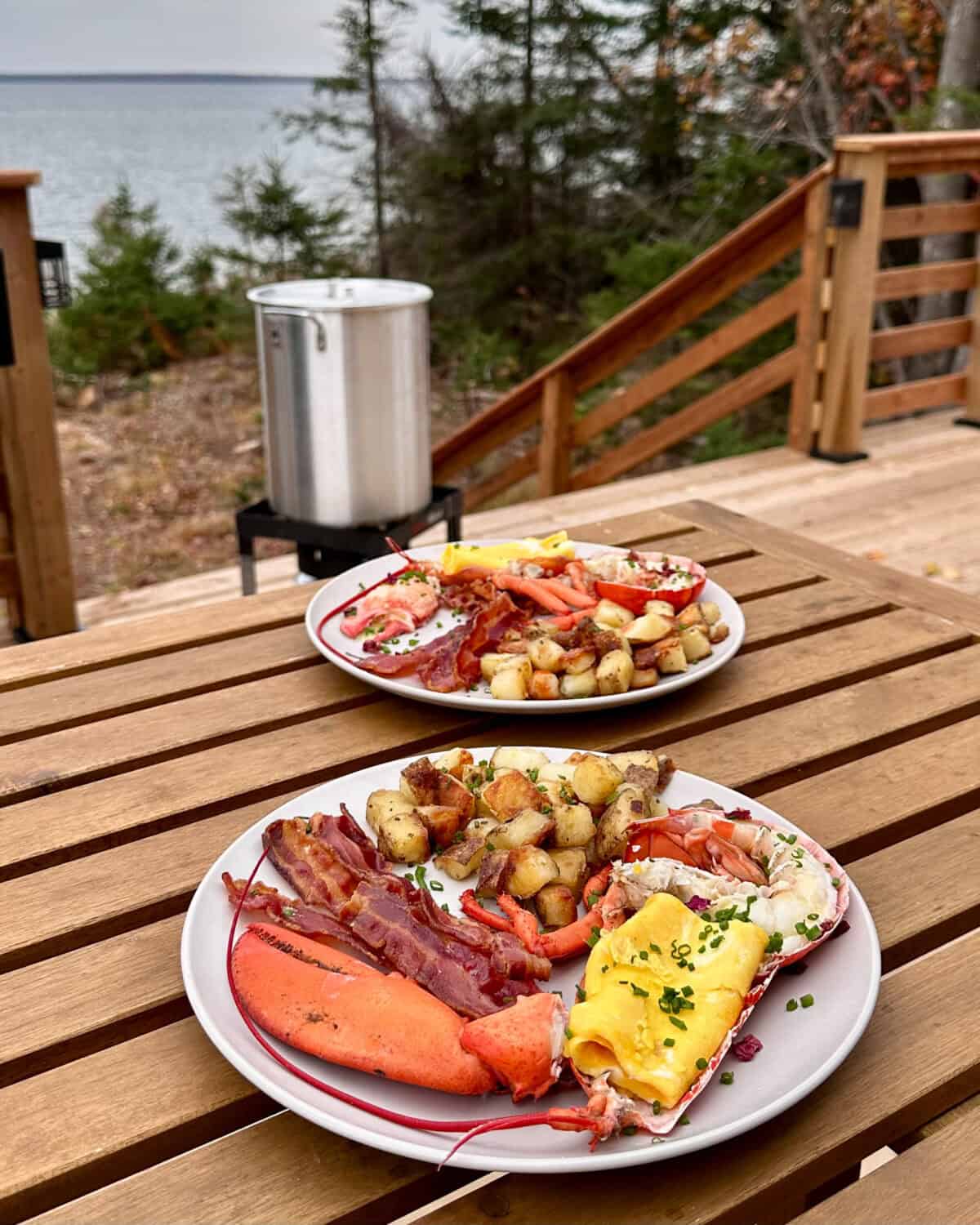 Two plates with a split lobster and eggs served with bacon and homefries.