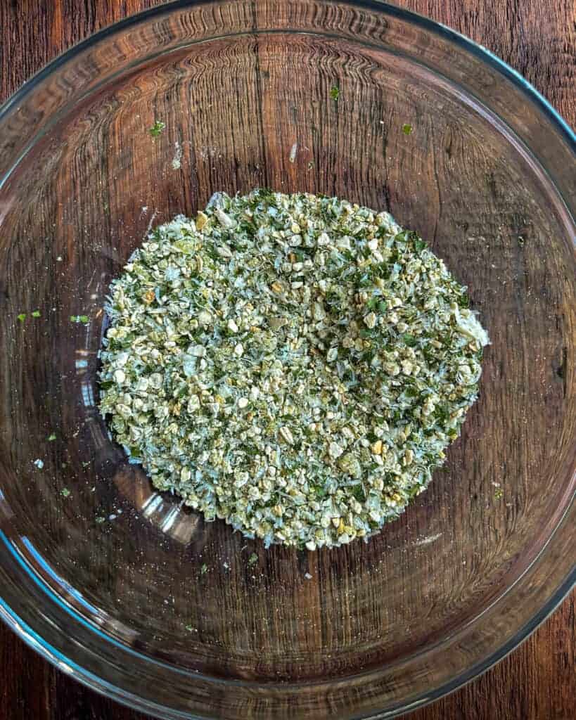 A large bowl, with a Paxo, parsley, Parmesan, garlic, black pepper mixture.