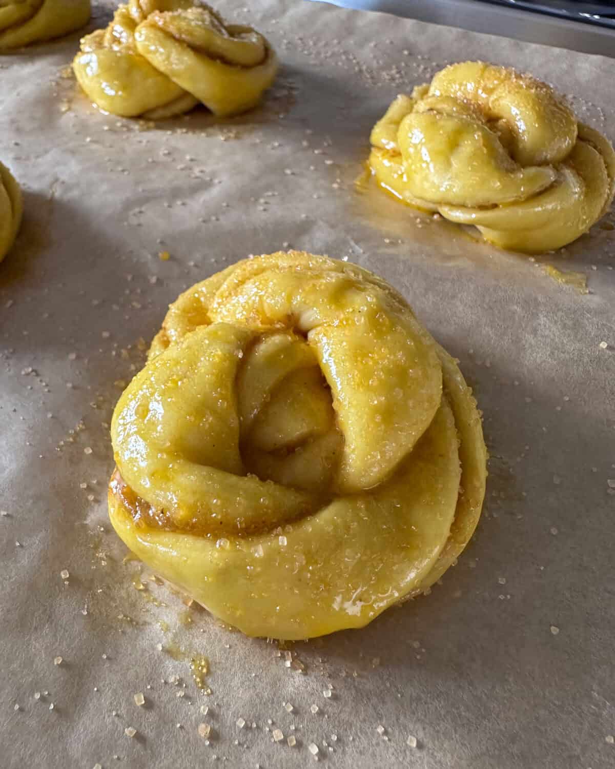 Brush the risen buns with egg wash and sprinkle with sugar.
