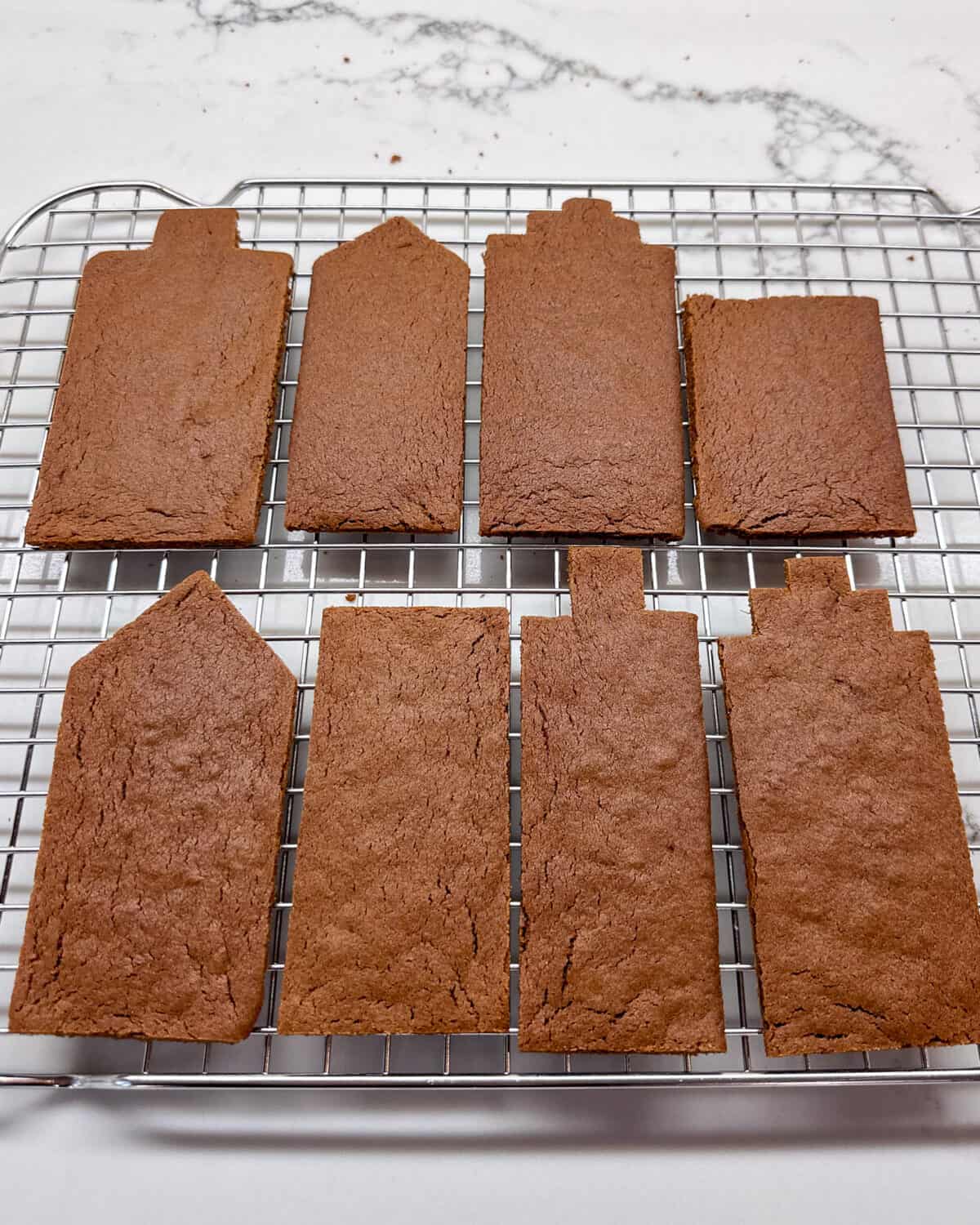 Eight baked gingerbread cookies trimmed up with a knife.