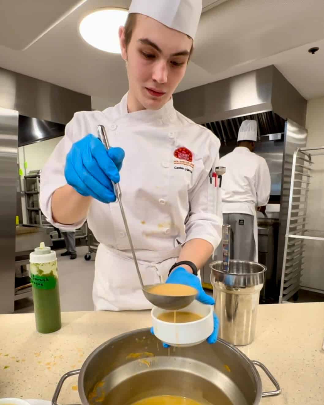 A junior chef preparing chowder in the marche.