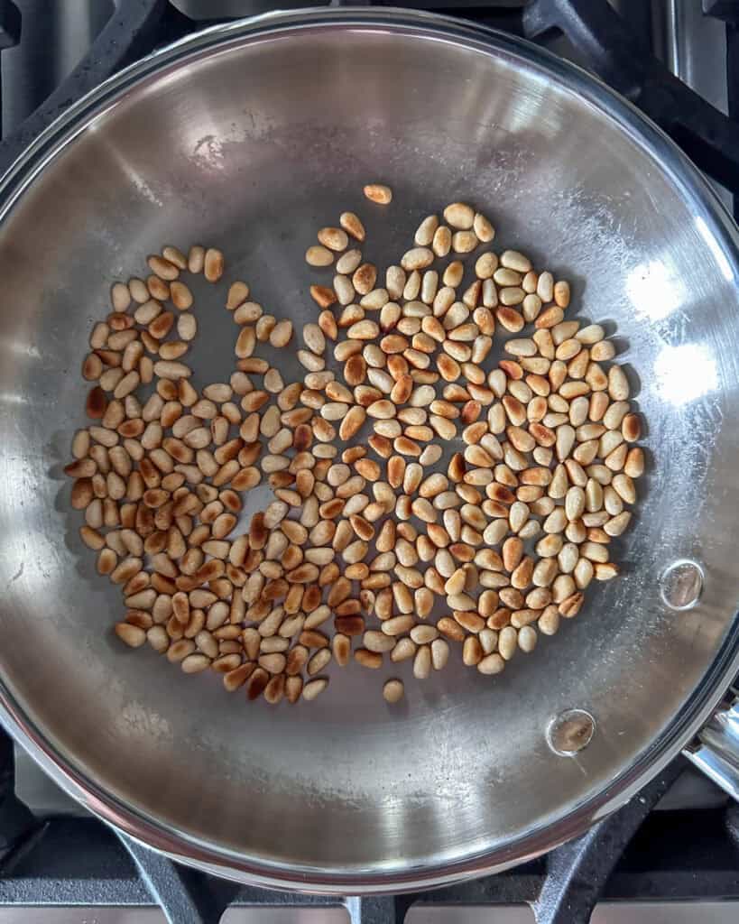 Toasting pine nuts in a skillet.