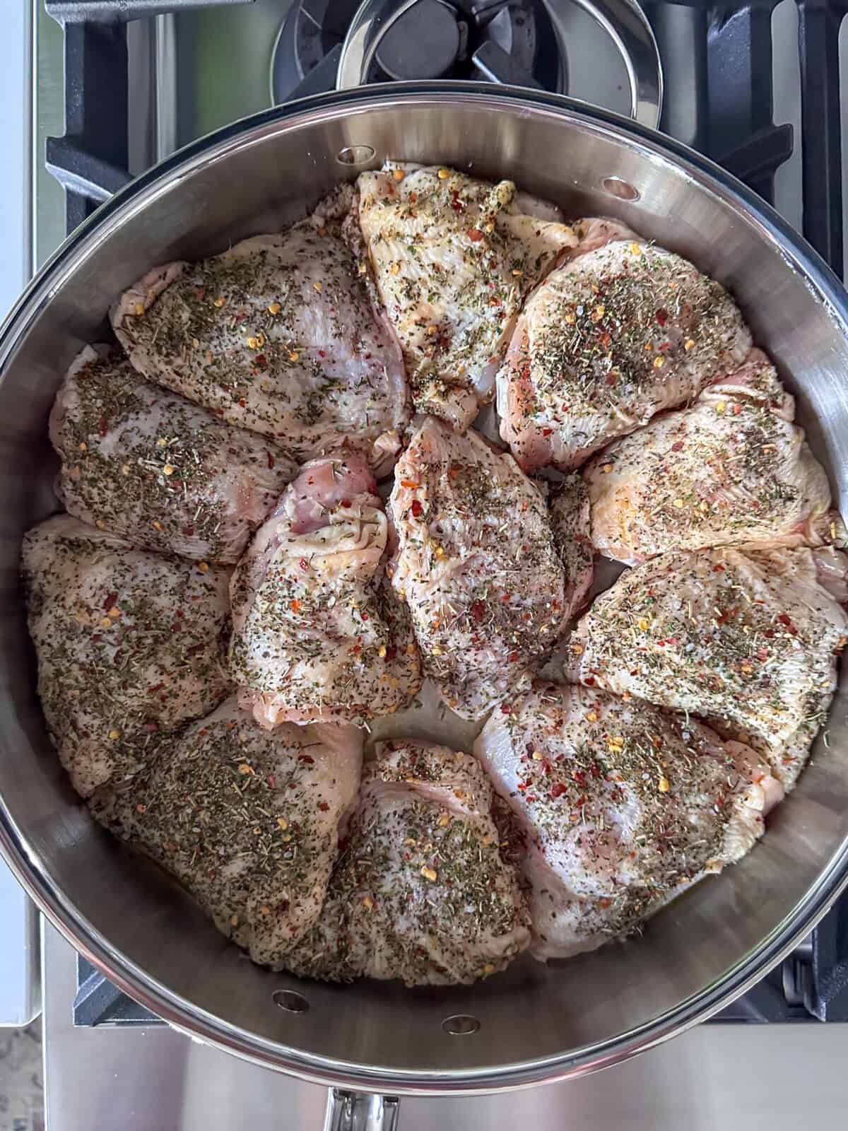Chicken thighs with herbs getting seared in a pan.