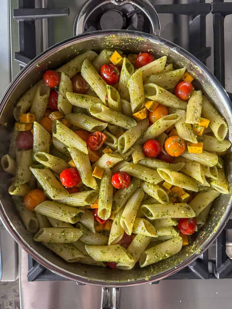 A pan of pesto pasta with tomatoes and squash about to get baked.
