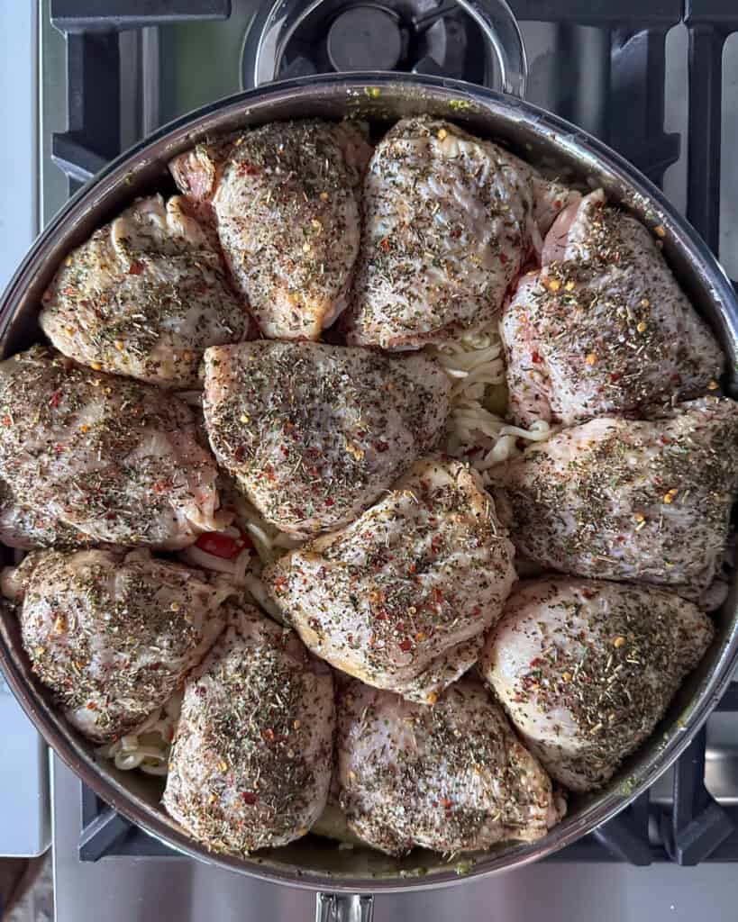 Chicken thighs over the pesto pasta ready to get baked.