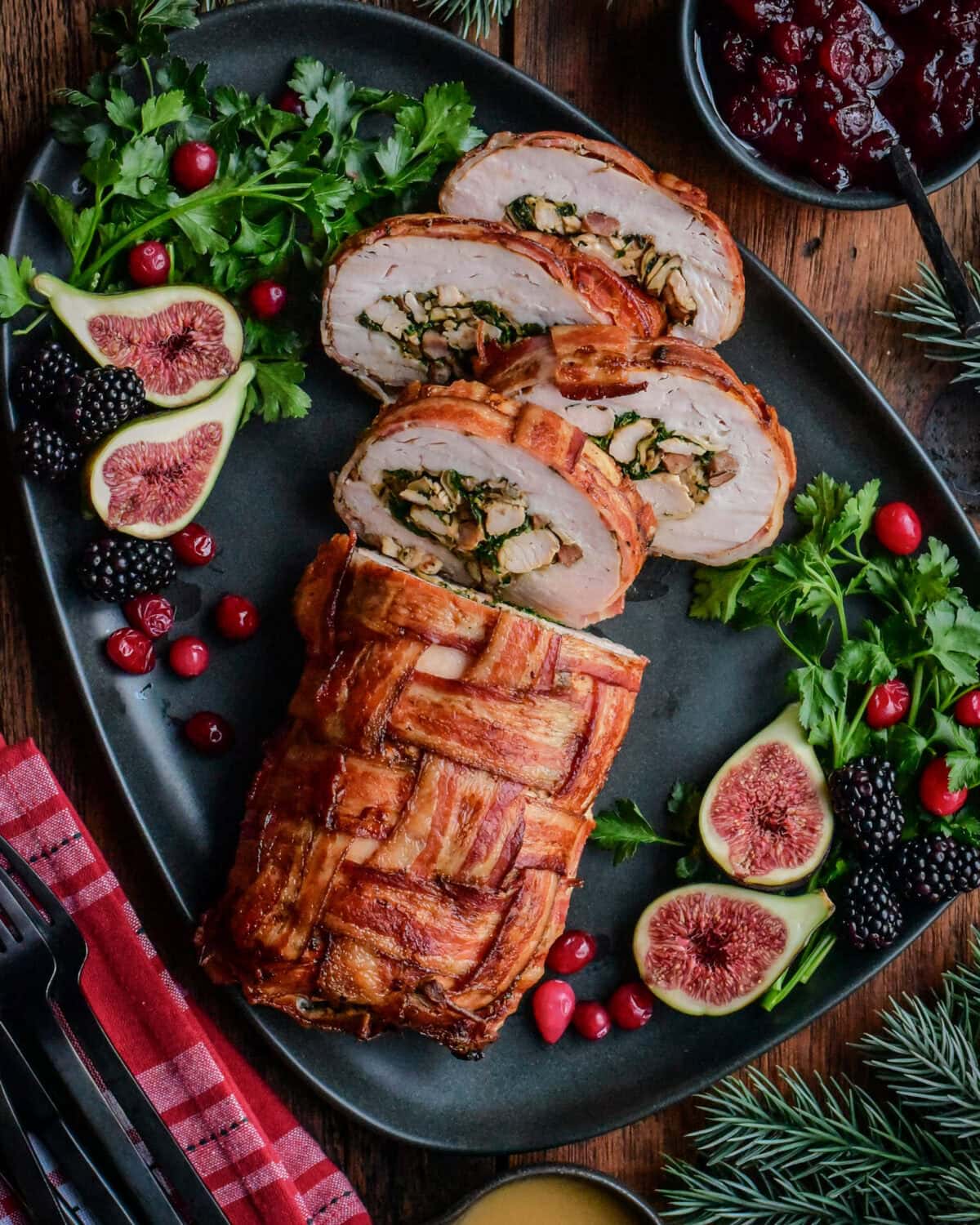 Bacon-Wrapped Stuffed Turkey Breast sliced on a platter revealing the stuffing.