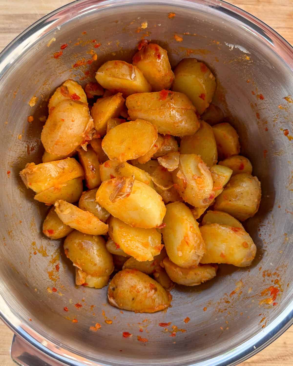 For this Italian bomba hot pepper sauce recipe toss the sliced potatoes in a bowl with the Bomba Sauce, ensuring all pieces are evenly coated.
