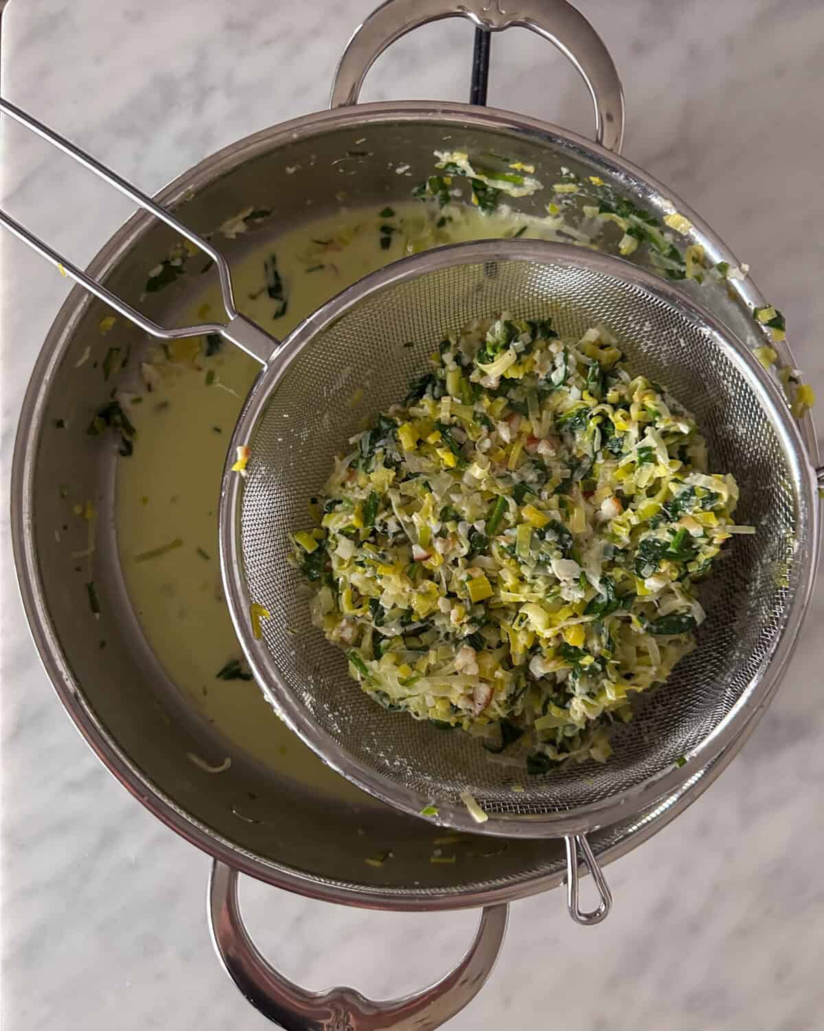 Strain the filling really well over a bowl, reserving the liquid for the sauce. The leeks should be as dry as possible.