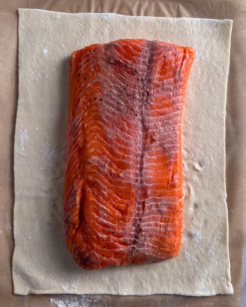 Place the seasoned salmon in the center of the rolled-out pastry (positioned skin-side up for better presentation, though the skin has been removed).