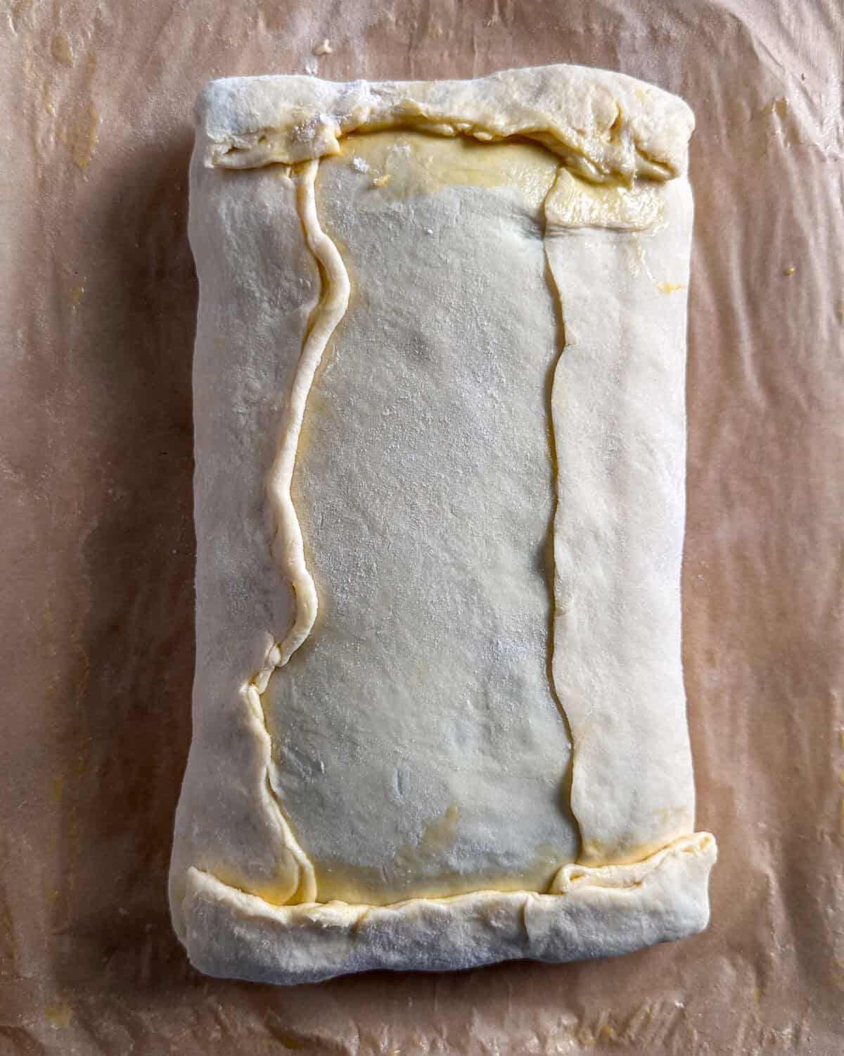 Brush the bottom pastry edges with egg wash, then carefully fold the edges over to seal.