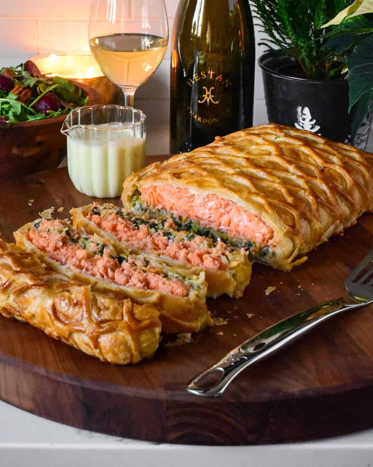 A sliced salmon en route with Leeks on a cutting board with wine and sauce.