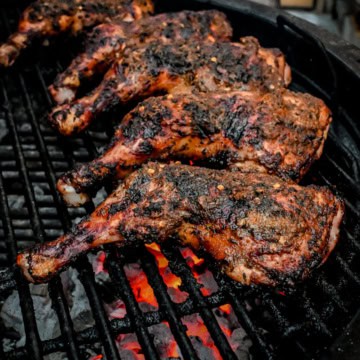 Five jerk chicken leg quarters on the BBQ.