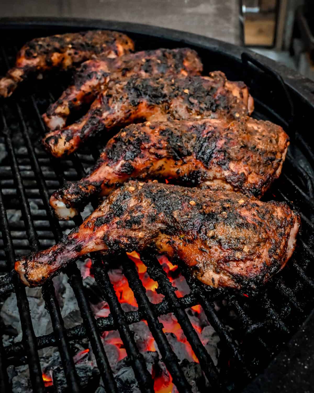 Five jerk chicken leg quarters on the BBQ.