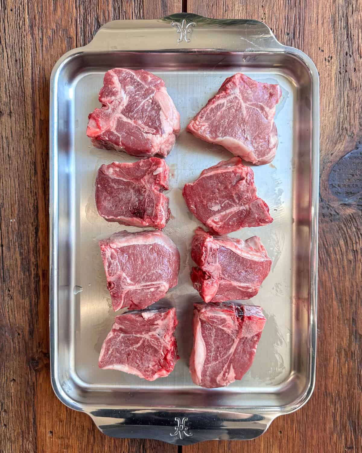 Eight thick cut lamb loin chops on a tray.
