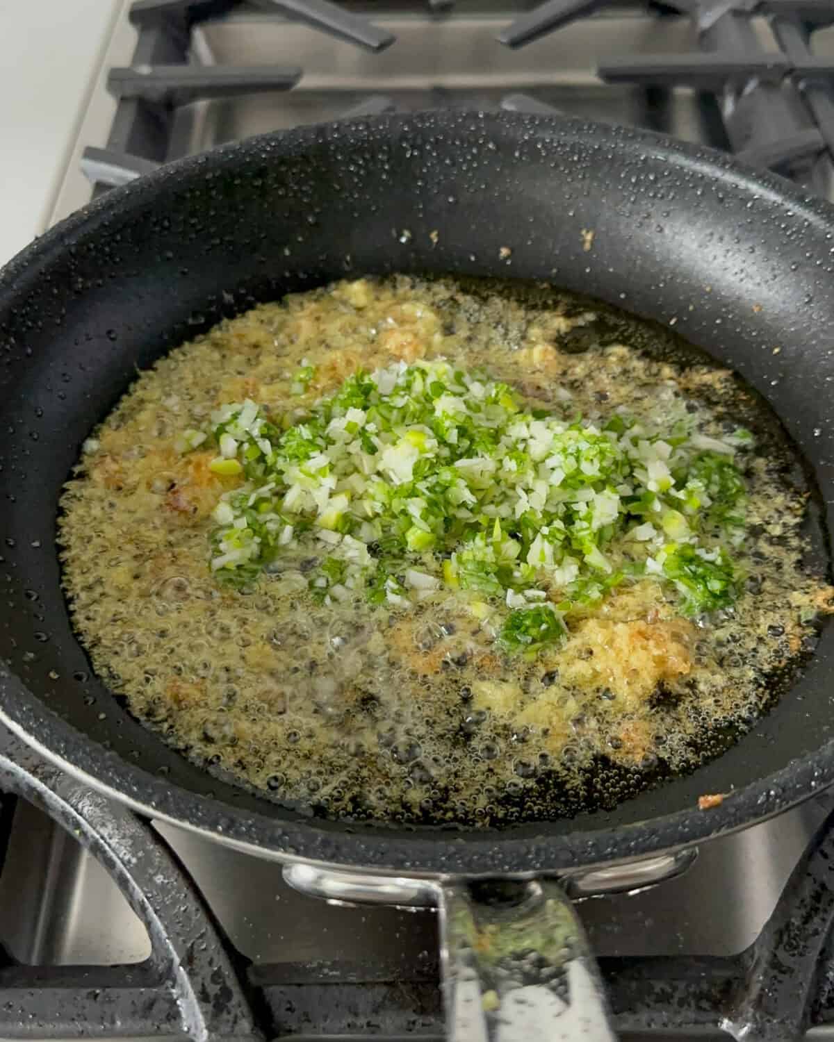 A skillet with a scallion ginger sauce getting made.