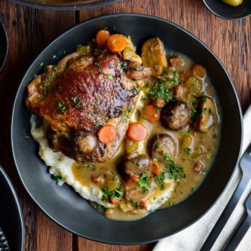 A braised turkey thigh on a bed of mashed potatoes with a rose wine sauce.