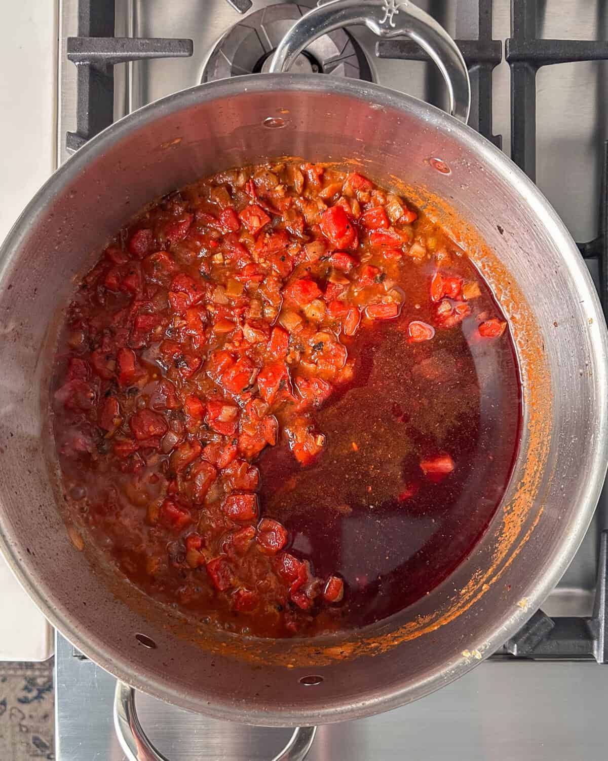 Add the diced tomatoes, red wine, to the lamb stew and bring to a boil.