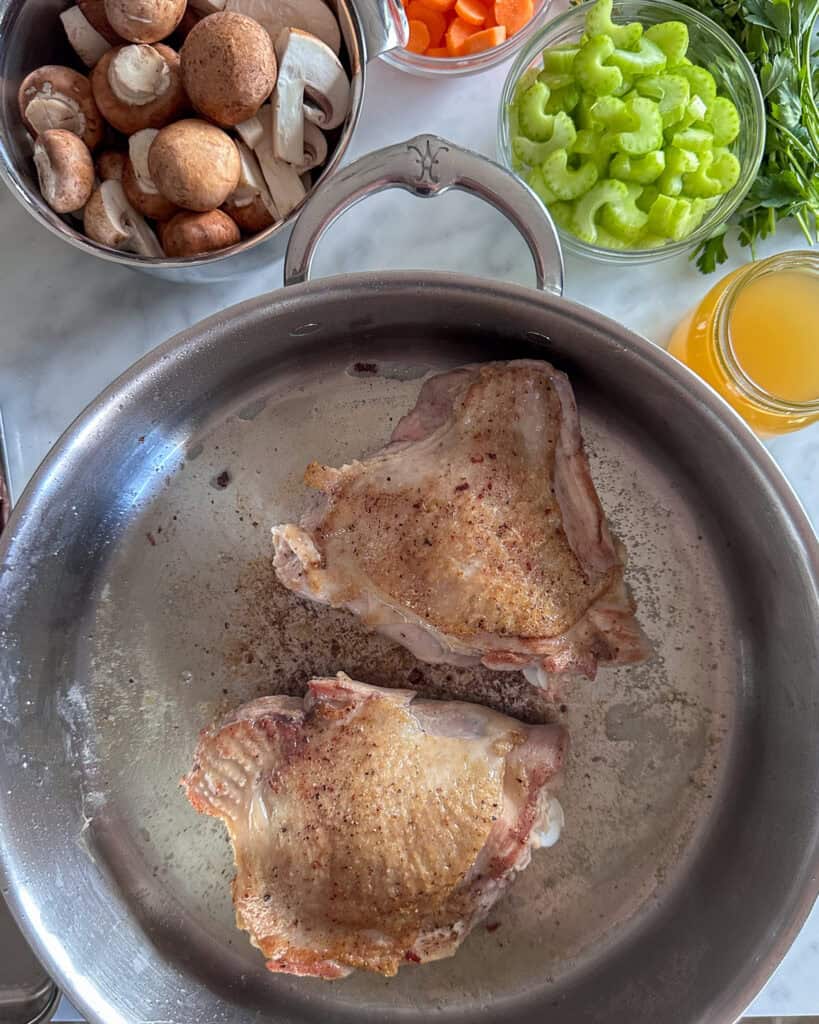Browning two turkey thighs at a time in a pan, skin side up, for 5 minutes until golden.
