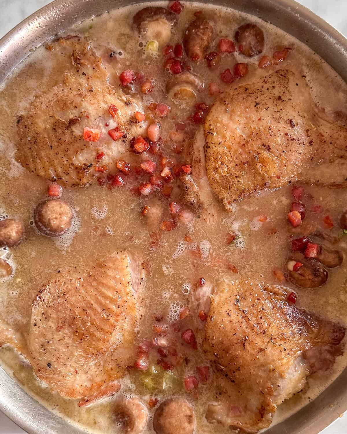 Return the turkey thighs back into the Au Vin Rosé sauce to cook.
