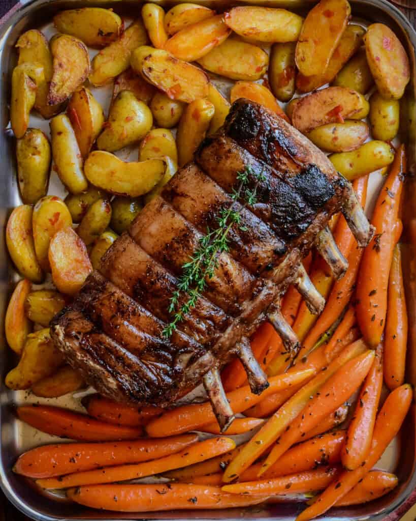 A roasted maple glaze rack of pork served alongside bomba potatoes and citrus orange-glazed carrots.