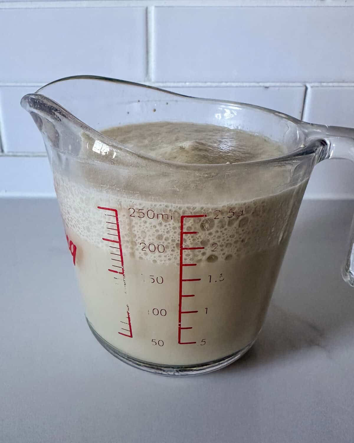 A measuring cup with activated and frothy yeast.