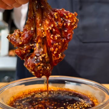A grilled gochujang butterflied drumstick dipped into the sauce.
