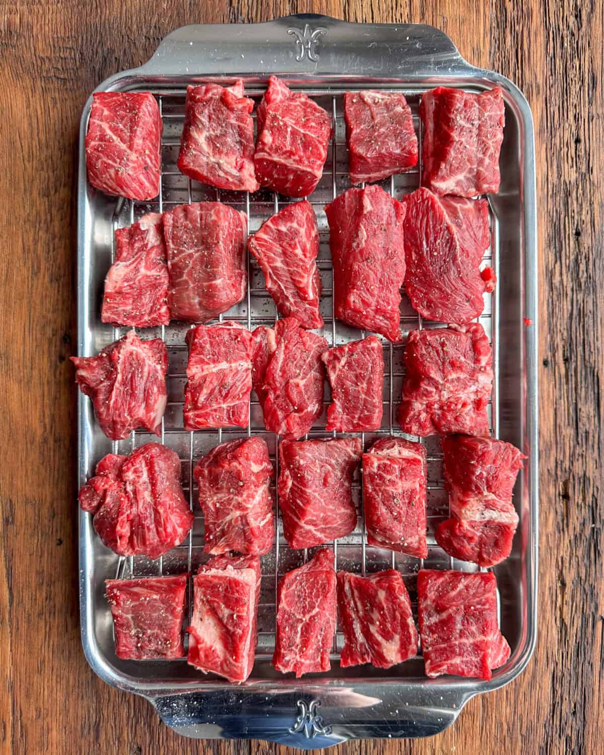 Seasoned beef cubes on a rack for a beef stew recipe in a dutch oven.