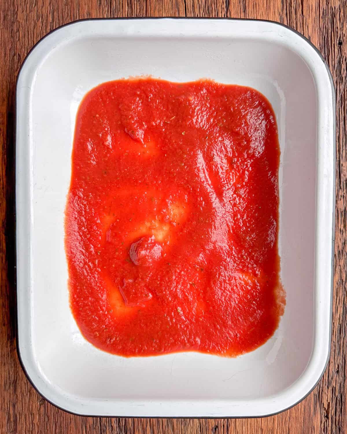 our a thin layer of the tomato sauce into the baking dish.