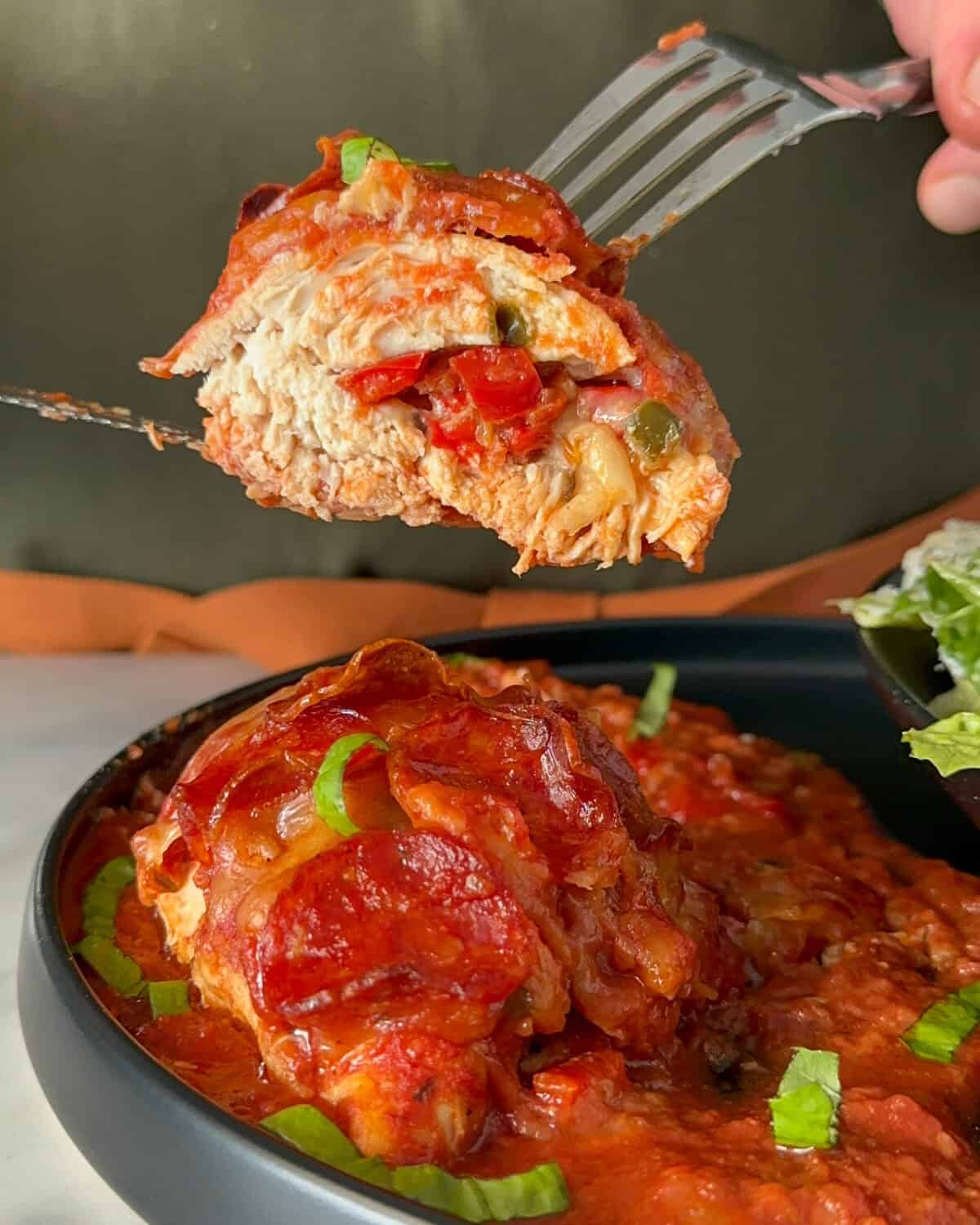 A cut piece a mozzarella pepperoni stuffed chicken breast.