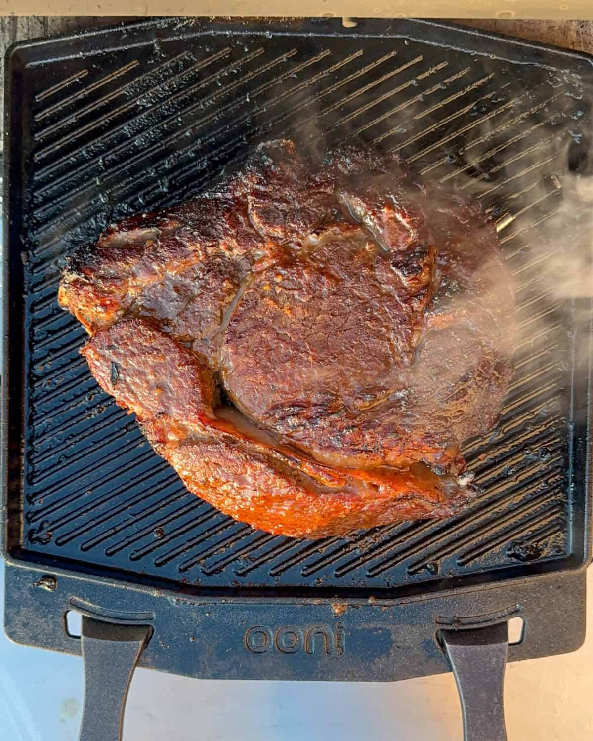 A prime rib searing on an Ooni Grizzler Plate.