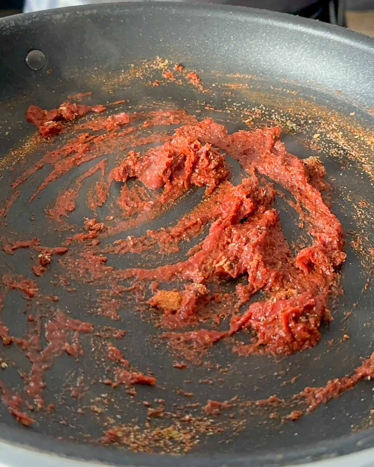 Garlic, spiced and tomato paste mixed in a pan.