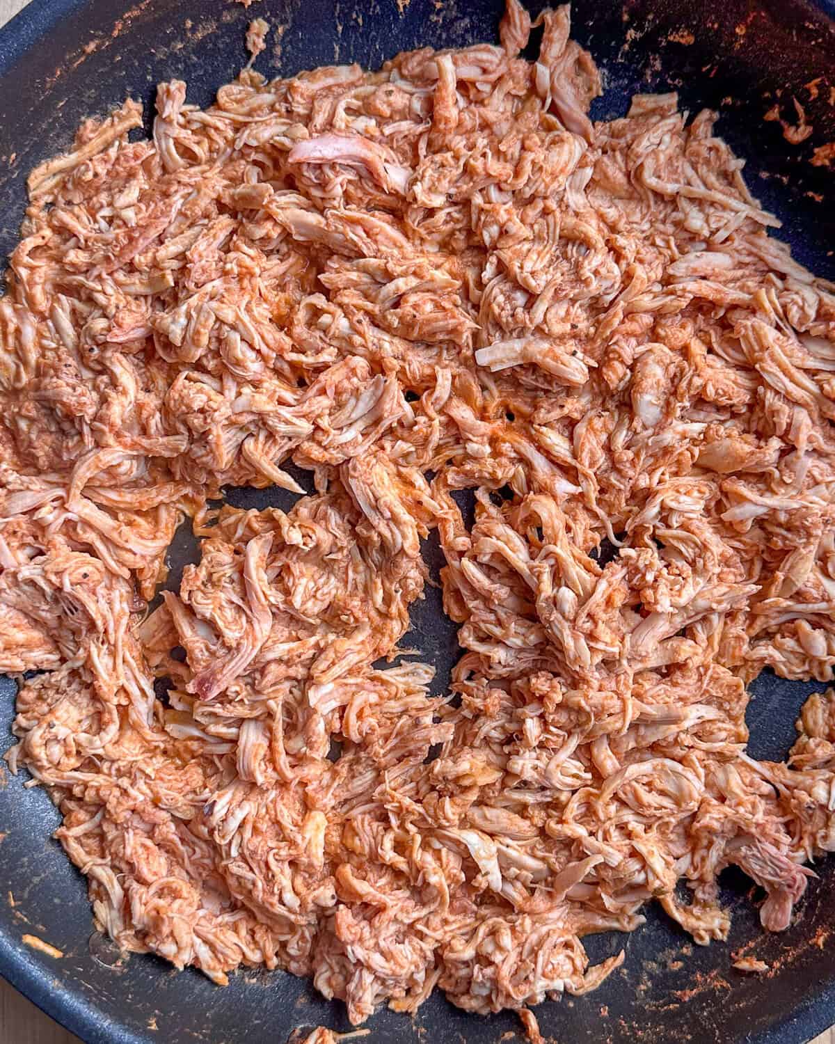 Seasoned and sauced shredded chicken for a Crispy Smashed Potato Tacos / Tostadas recipe.