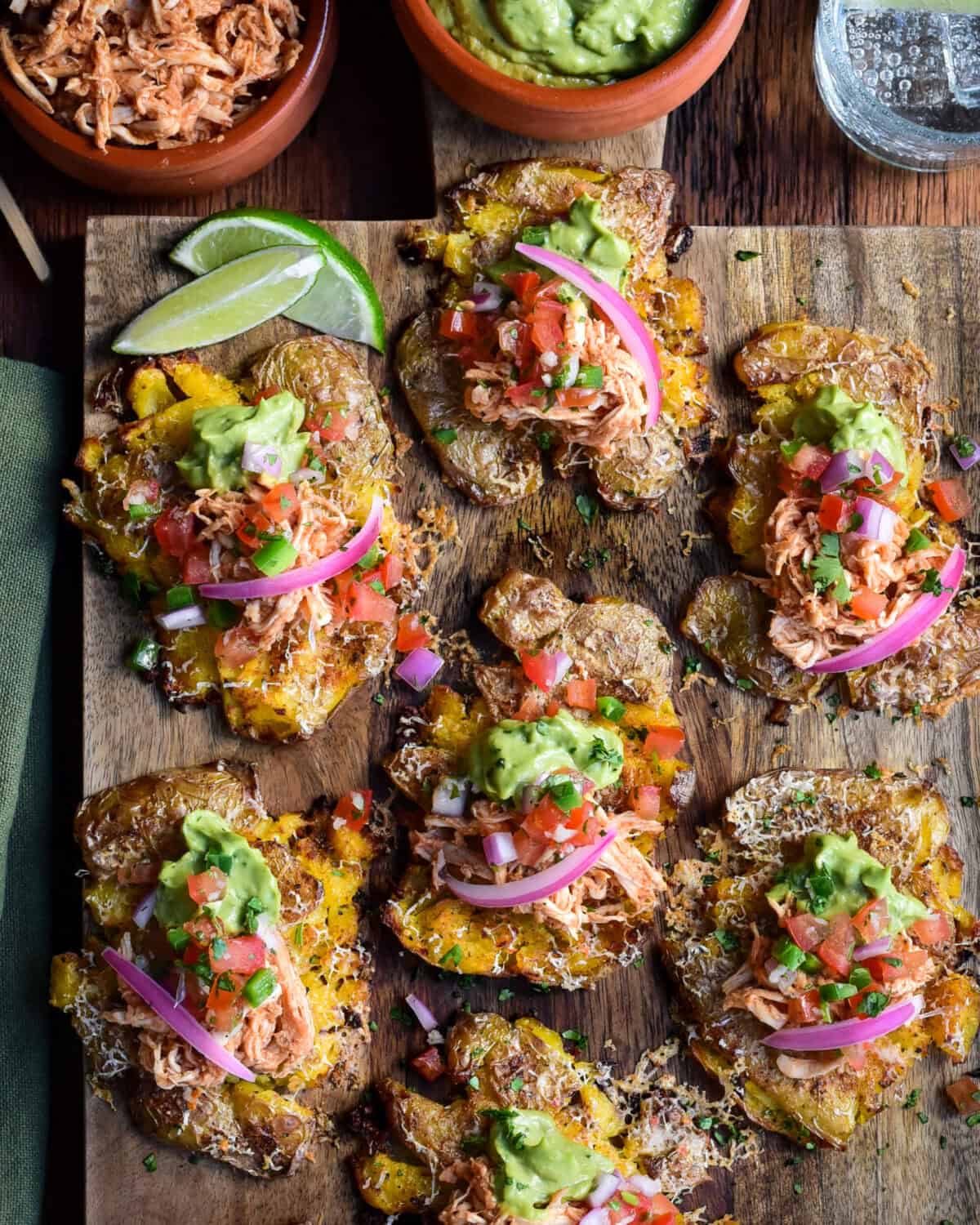 A board with Crispy Smashed Potato Tacos (or Tostadas) Topped with spiced rotisserie chicken, cheese, and fresh toppings like guacamole and Pico de Gallo,