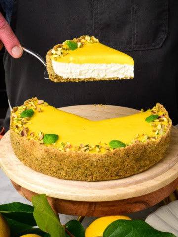 A slice of lemon curd pie with graham cracker crust getting lifted out of the pie.