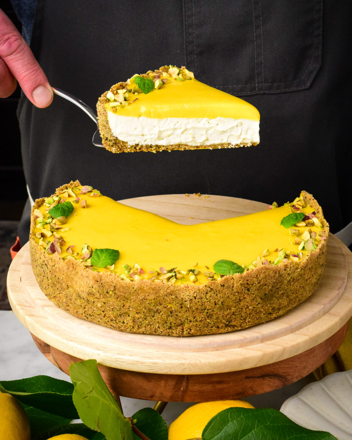 A slice of lemon curd pie with graham cracker crust getting lifted out of the pie.
