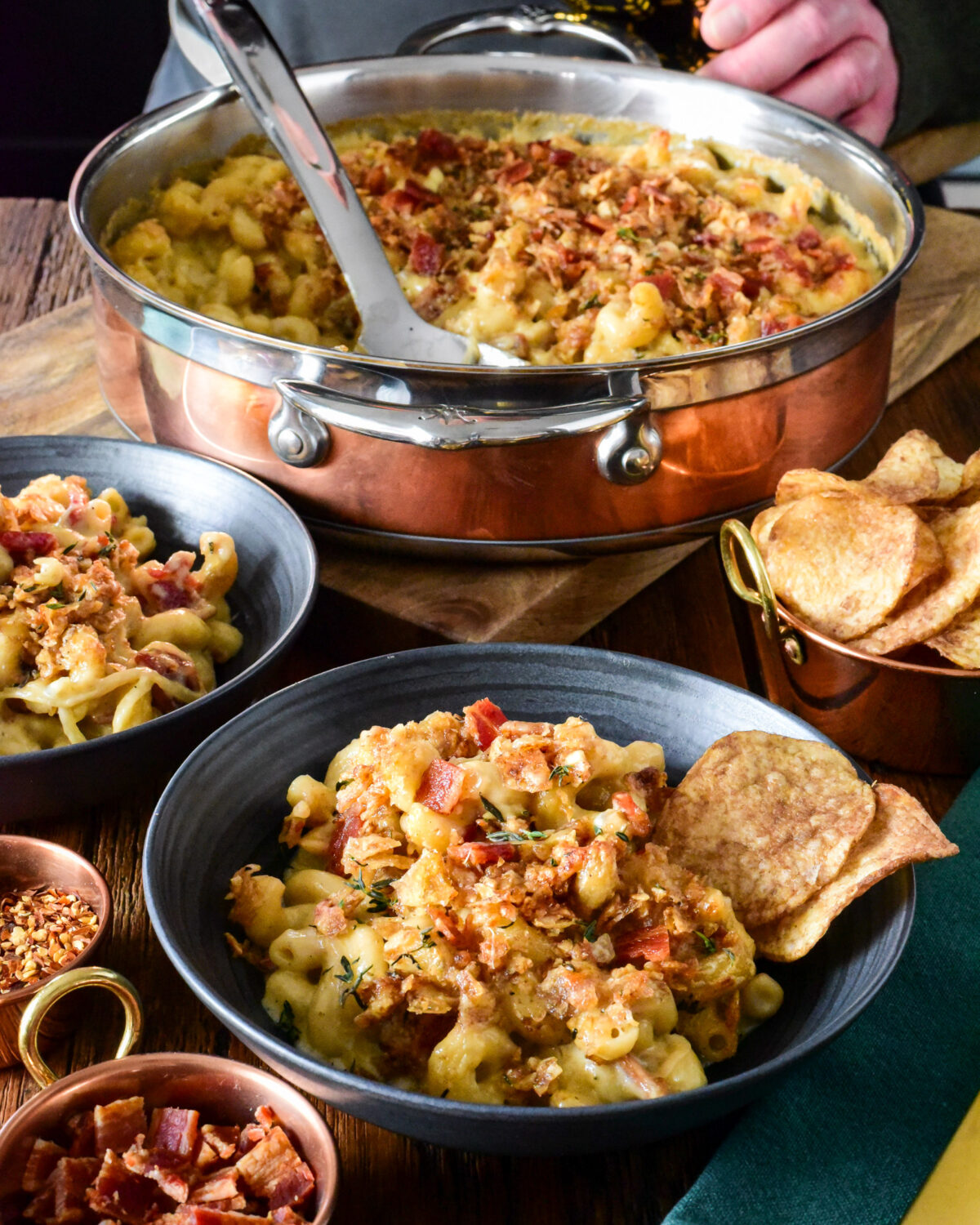 A copper pot and two bowls of Guinness Mac and Cheese with Irish Whiskey Onions. Served with chips and Guinness.
