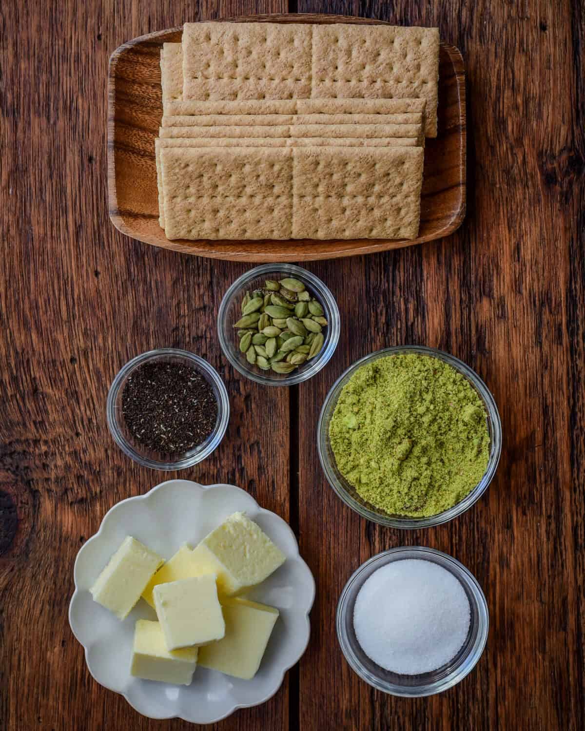 Ingredients for a graham cracker pie crust recipe with ground pistachios, cardamom, and Earl Grey tea leaves.
