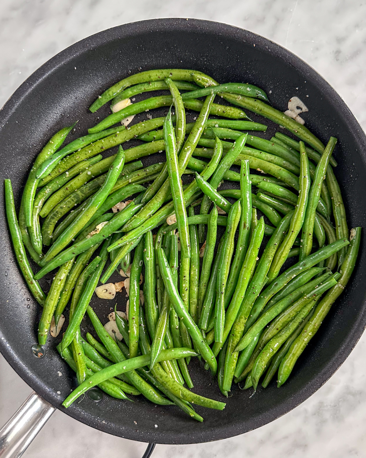 Blistered green beans with garlic in a skillet.