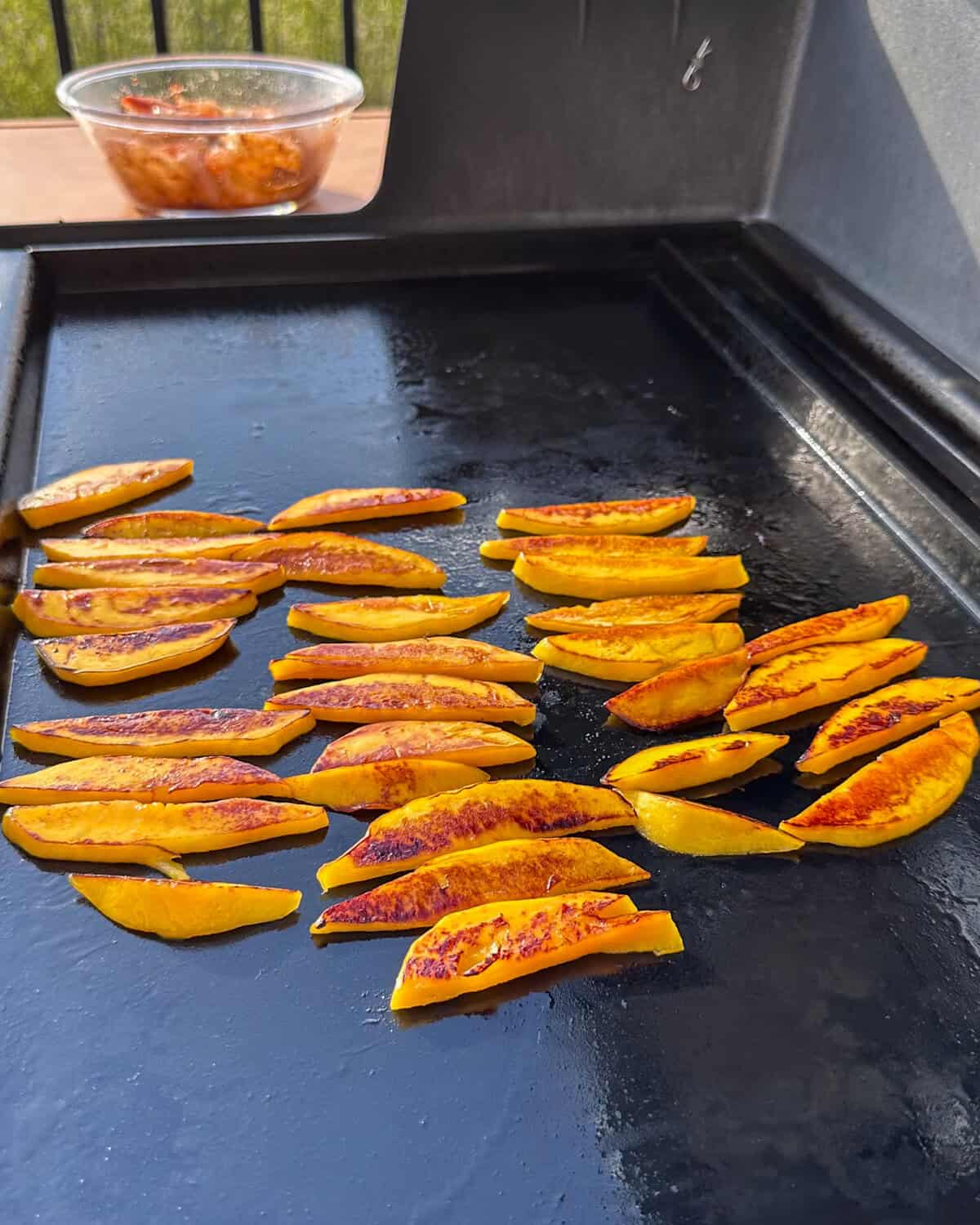 Griddled mango slices on a griddle.