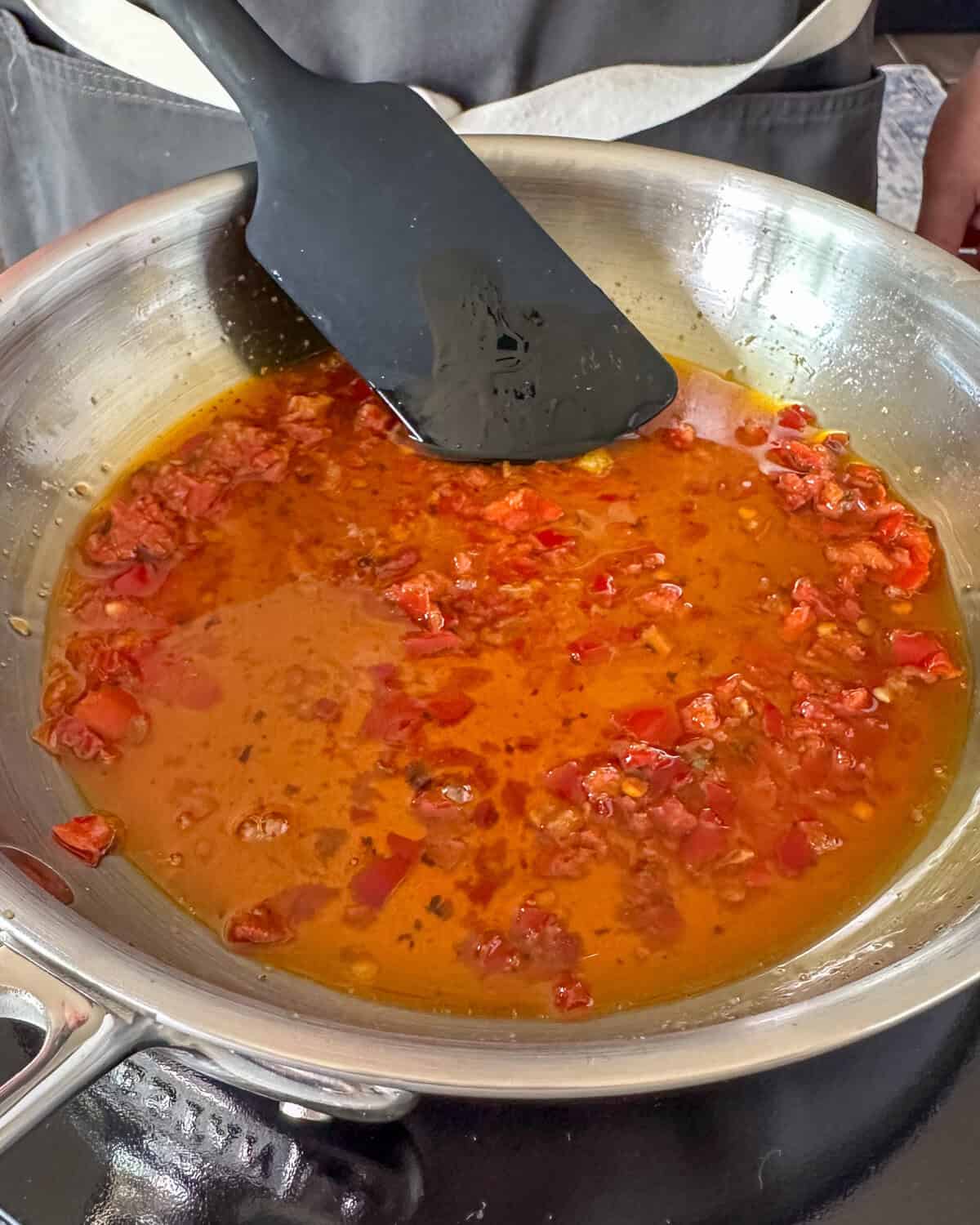 Stir in the crushed chili peppers for the Calabrian chili oil recipe.