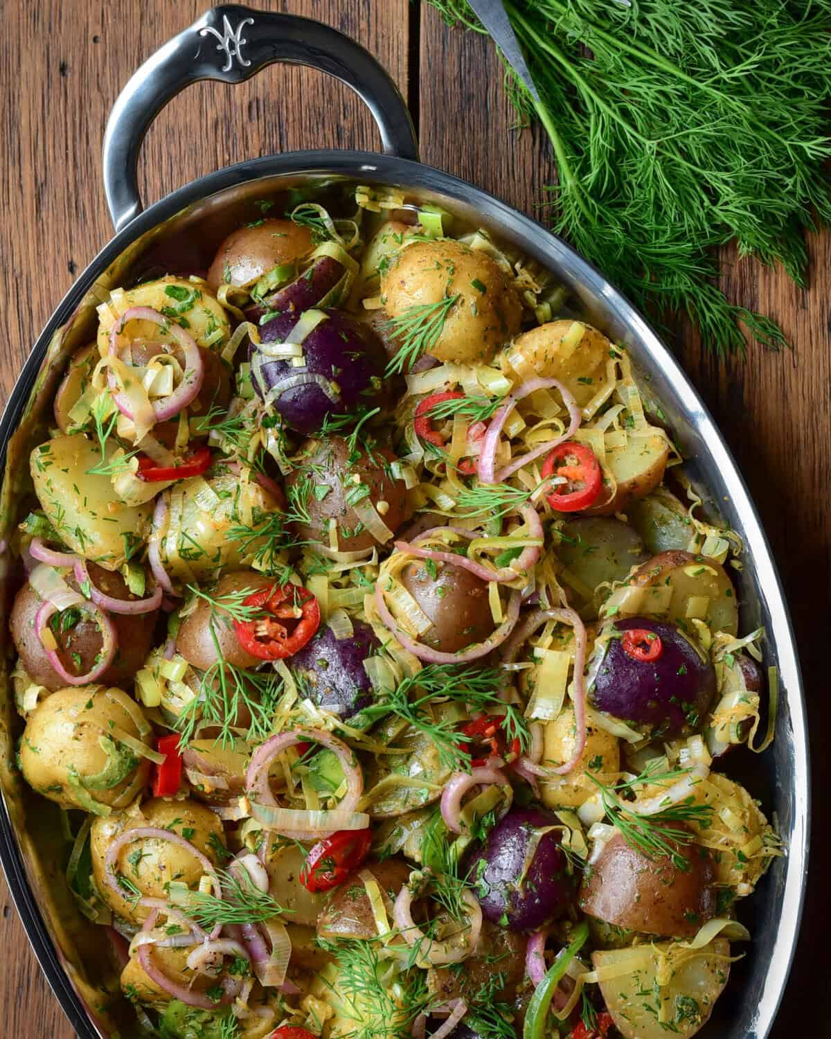 A Brown Butter Potato Salad with Leeks & Pickled Shallots on an oval platter and served with fresh dill.