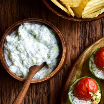 A bowl of an Easy Cucumber Mint Yogurt Dip (Zero Waste Recipe) served with ruffled chips and cucumber cups.