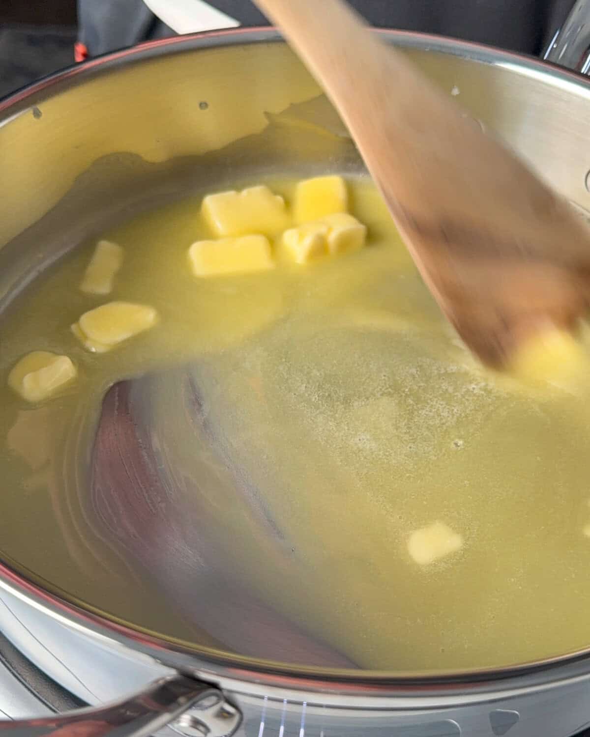 Stirring butter in a skillet with a wooden spoon.